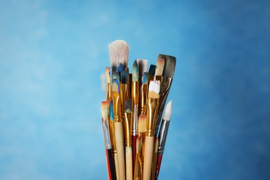 Photo of Many different paintbrushes on light blue background