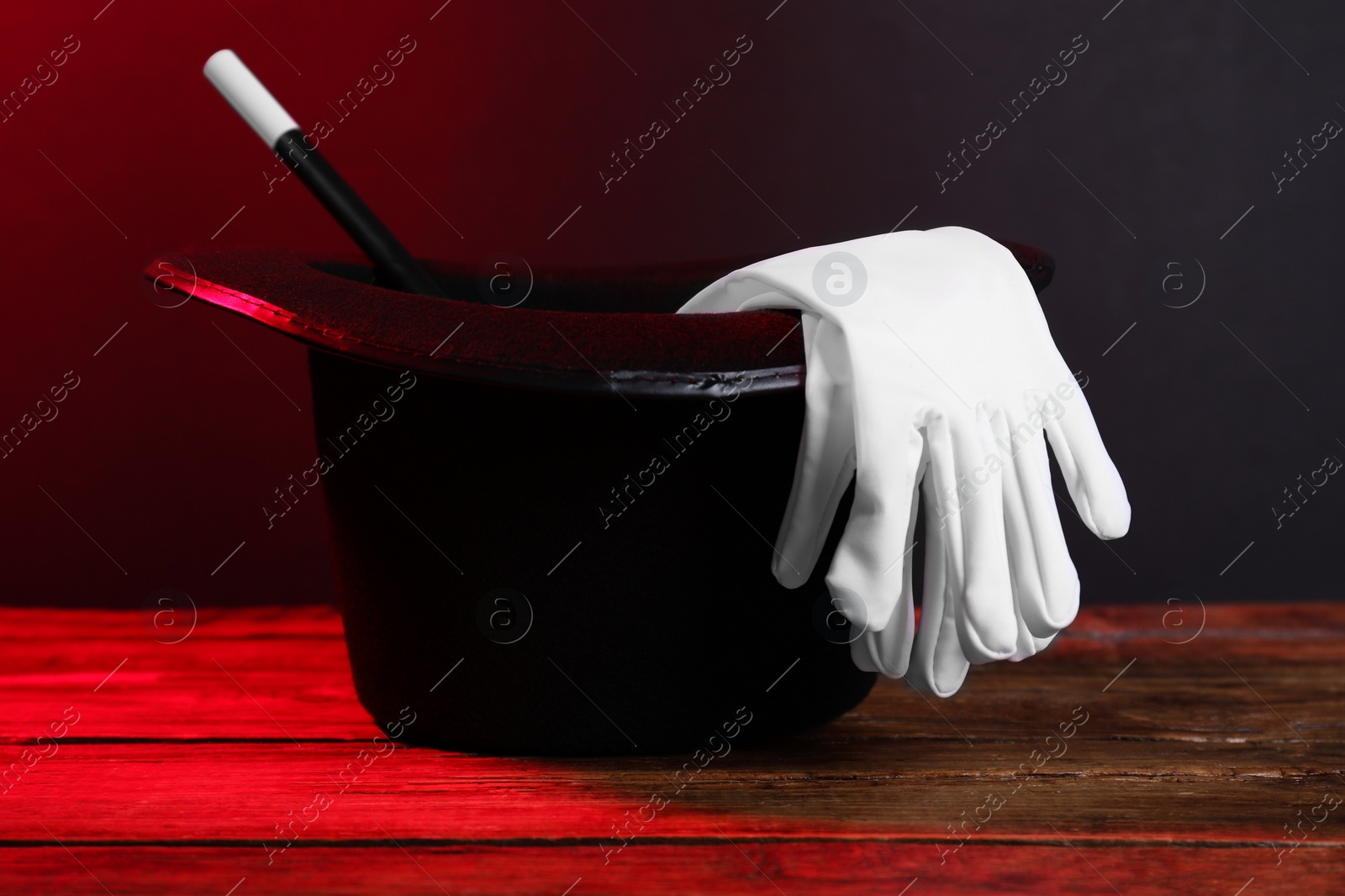 Photo of Black top hat, gloves and wand on wooden table. Magician equipment