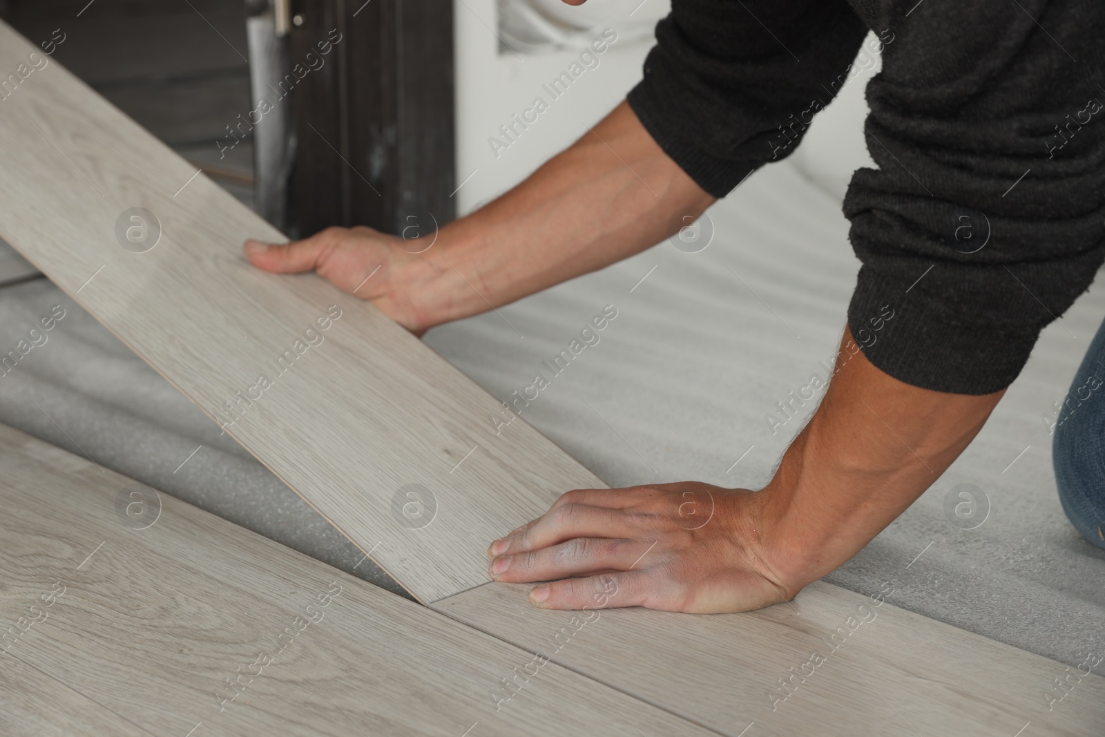 Photo of Worker installing new laminate flooring in room, closeup