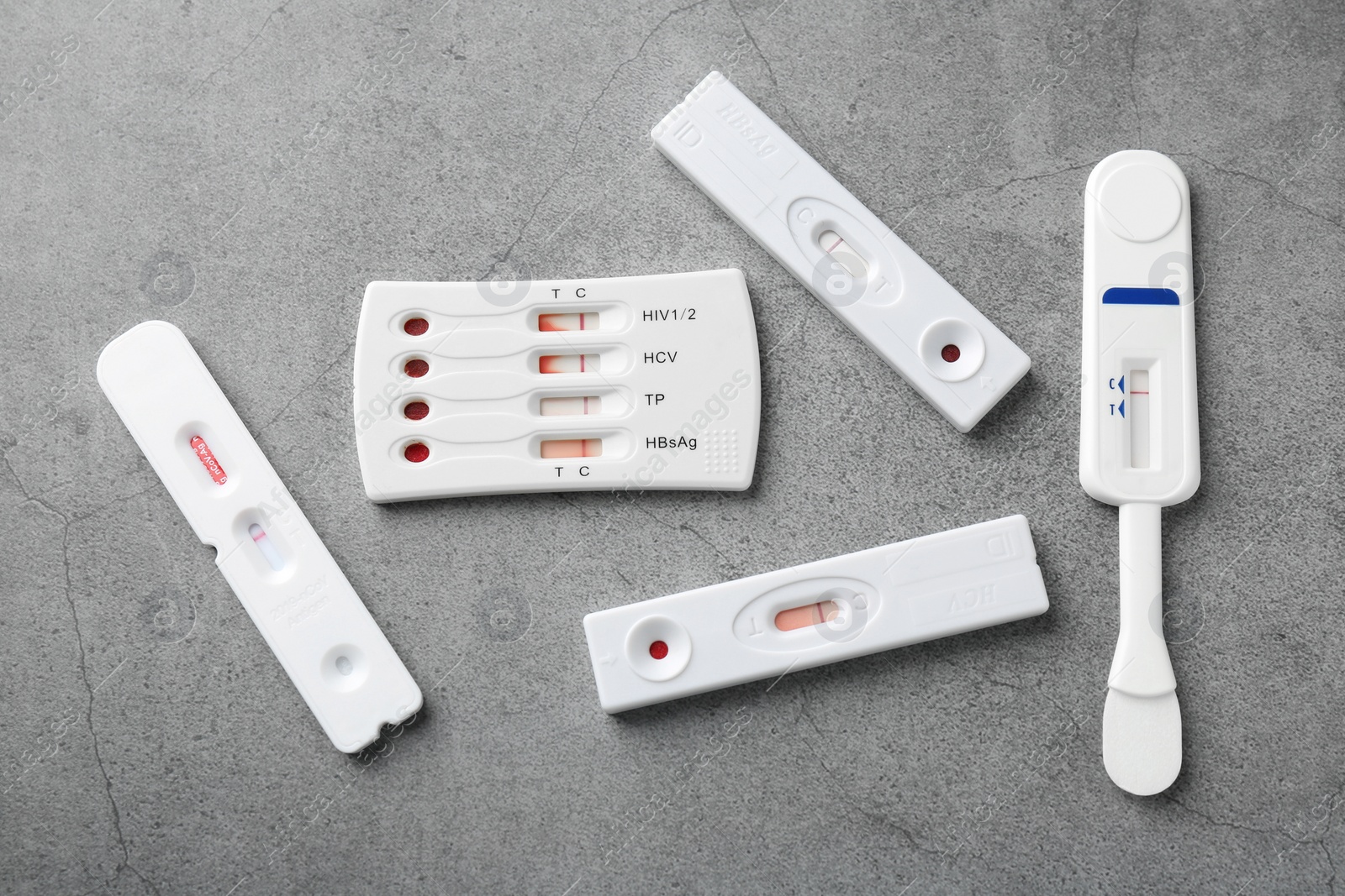 Photo of Different disposable express tests on grey table, flat lay