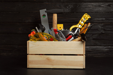 Photo of Wooden crate with different carpenter's tools on black table