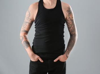 Photo of Young man with stylish tattoos on grey background