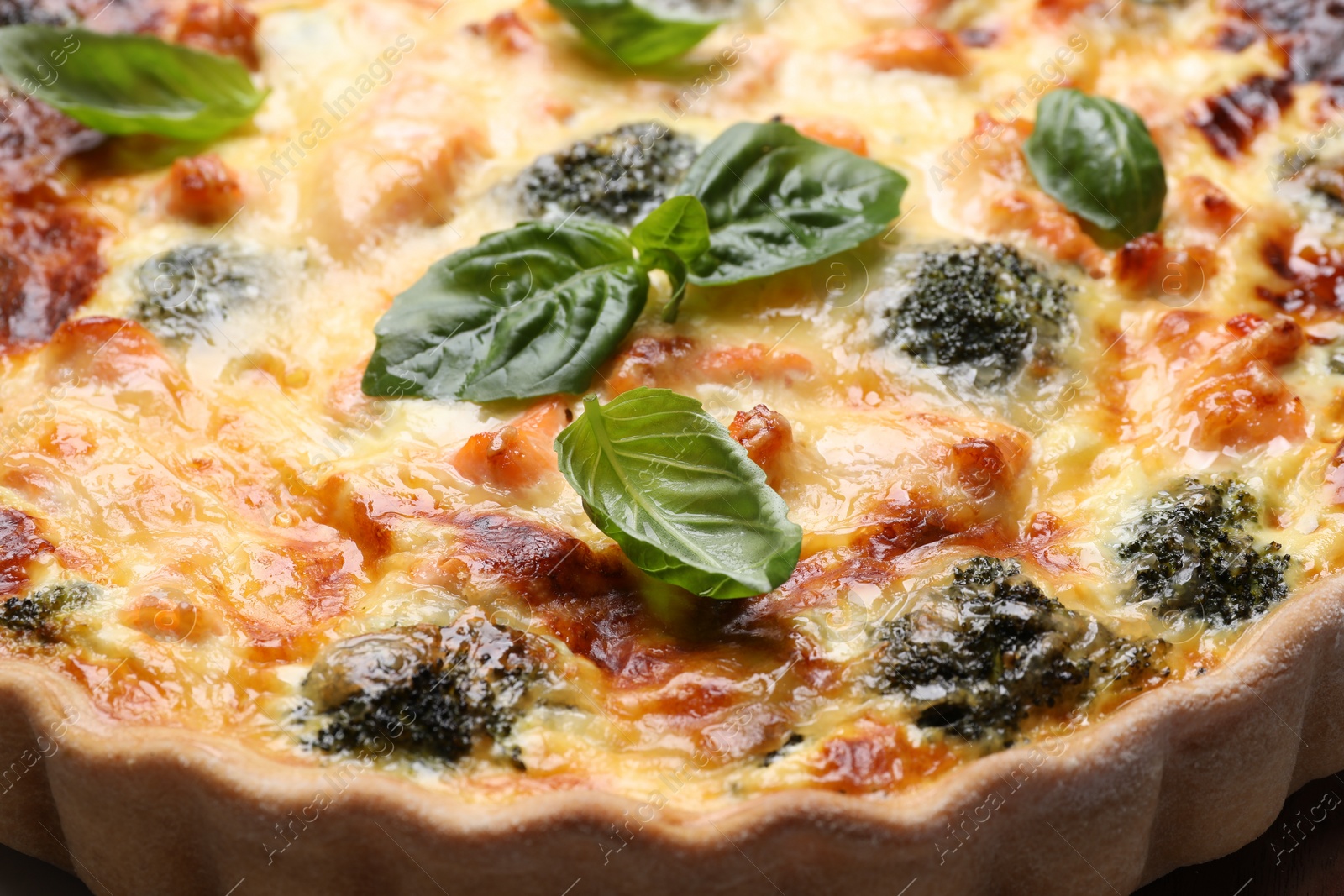 Photo of Delicious homemade quiche with salmon, broccoli and basil leaves, closeup