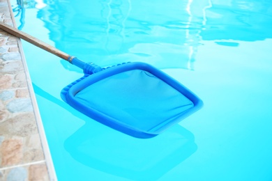 Photo of Cleaning outdoor pool with scoop net, closeup