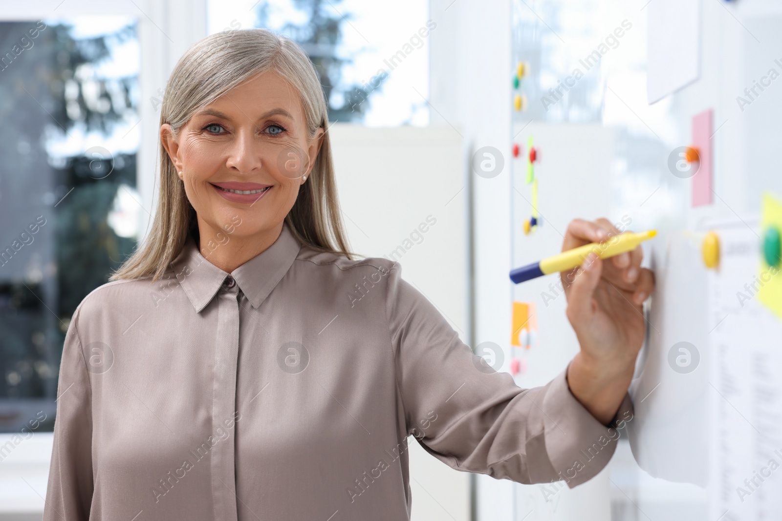 Photo of Professor explaining something with marker at whiteboard in classroom