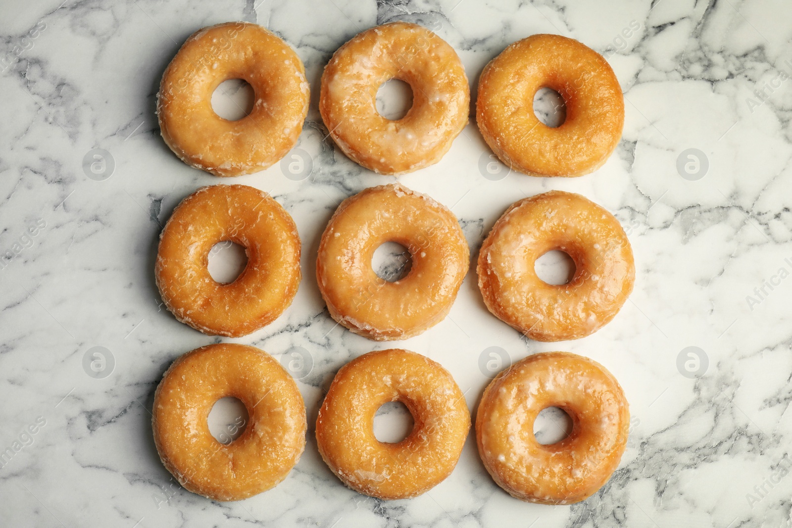 Photo of Delicious donuts on marble table, flat lay