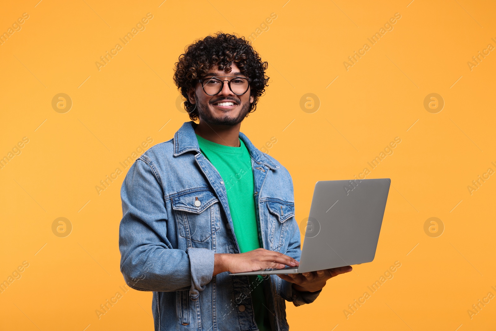 Photo of Smiling man with laptop on yellow background