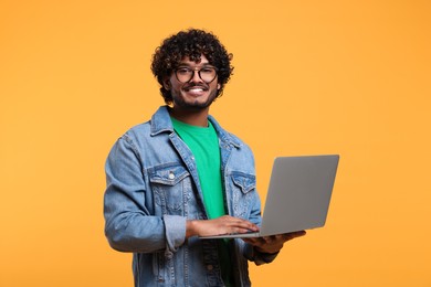 Smiling man with laptop on yellow background