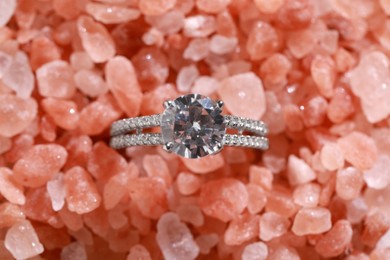 Photo of Luxury jewelry. Stylish presentation of elegant ring on sea salt, top view