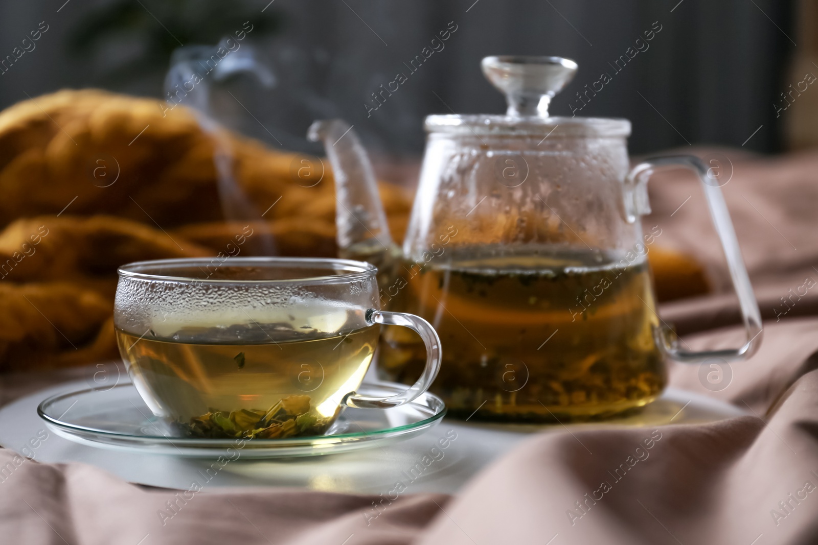Photo of Tray with cup of hot tea and teapot on bed
