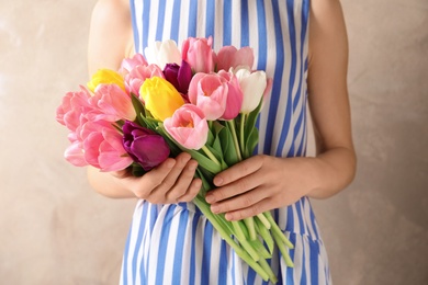 Photo of Girl holding bouquet of beautiful spring tulips on color background, closeup. International Women's Day