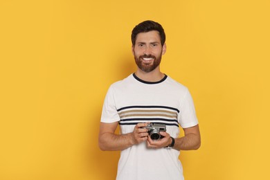 Man with camera on yellow background. Interesting hobby