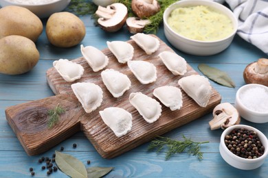 Photo of Raw dumplings (varenyky) and ingredients on light blue table
