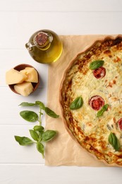 Photo of Delicious homemade cheese quiche and ingredients on white table, flat lay