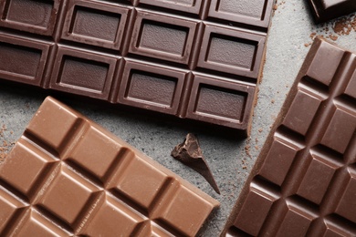 Different chocolate bars on grey background, top view