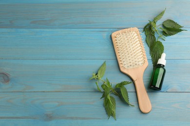Stinging nettle, cosmetic product and brush on light blue wooden background, flat lay with space for text. Natural hair care