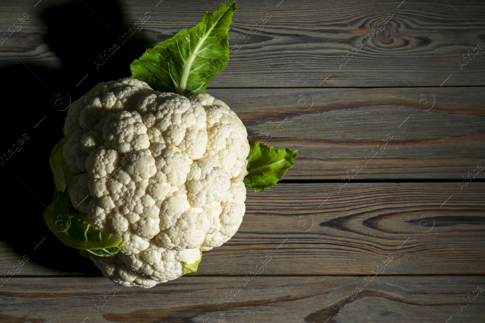 Photo of Whole fresh raw cauliflower on wooden table, top view. Space for text