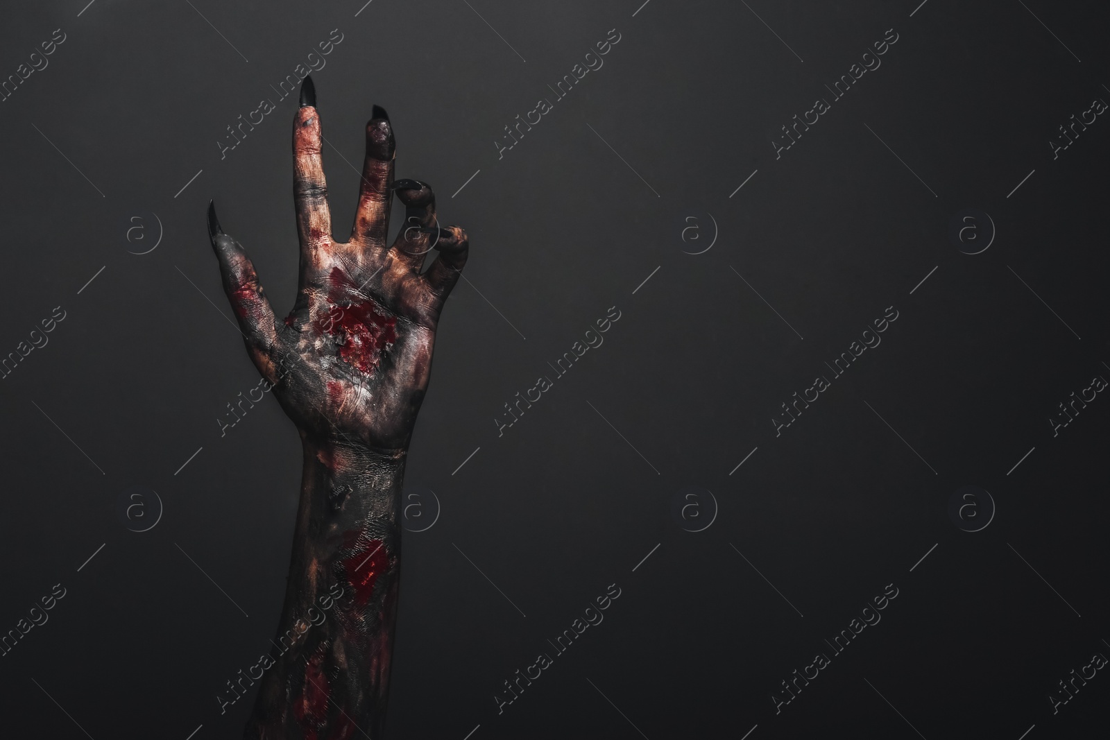 Photo of Scary monster on black background, closeup of hand with space for text. Halloween character