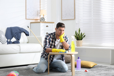 Photo of Lazy man procrastinating while cleaning at home