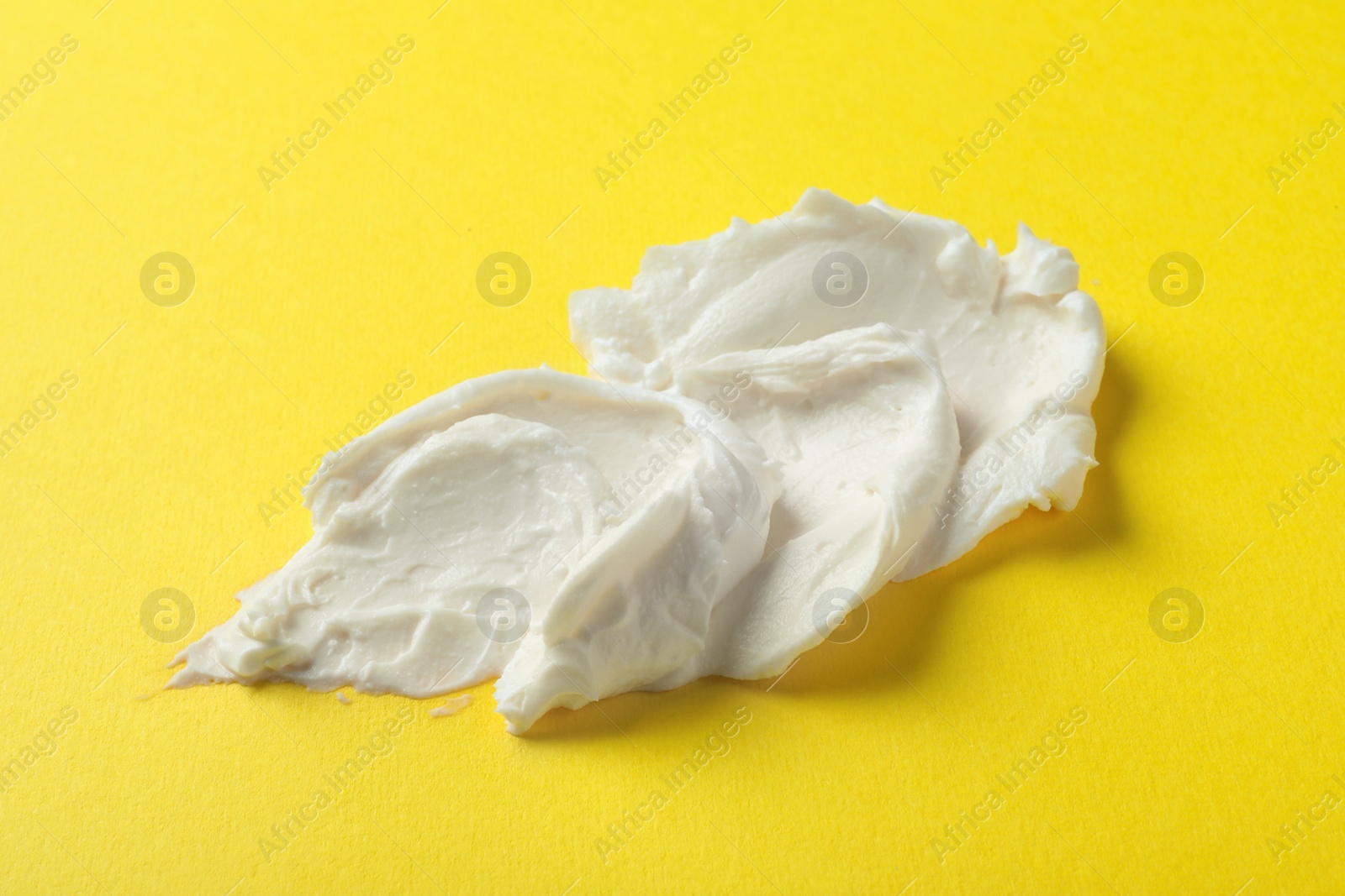 Photo of Smear of delicious cream cheese on yellow background