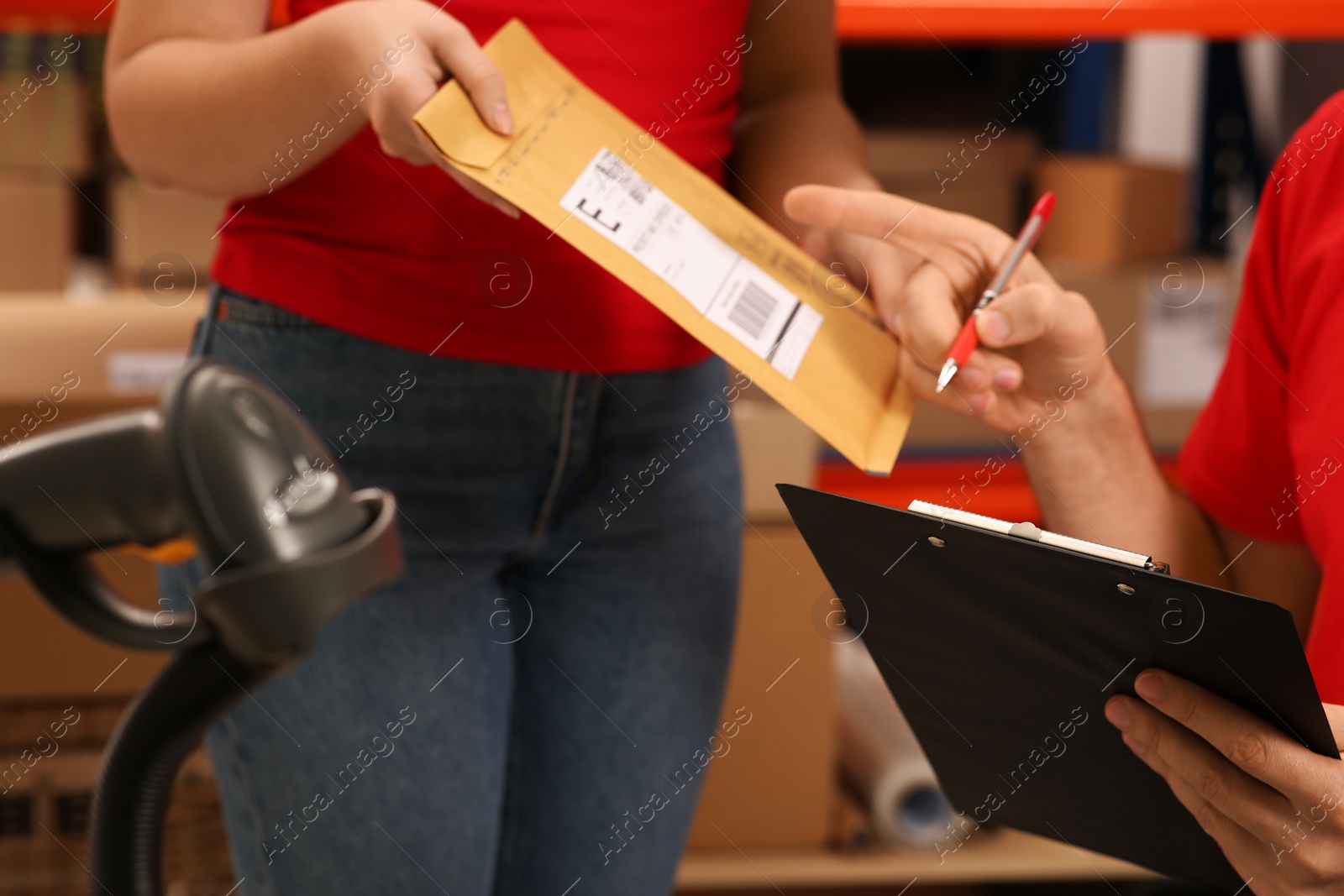 Photo of Post office workers checking parcel barcode indoors, closeup