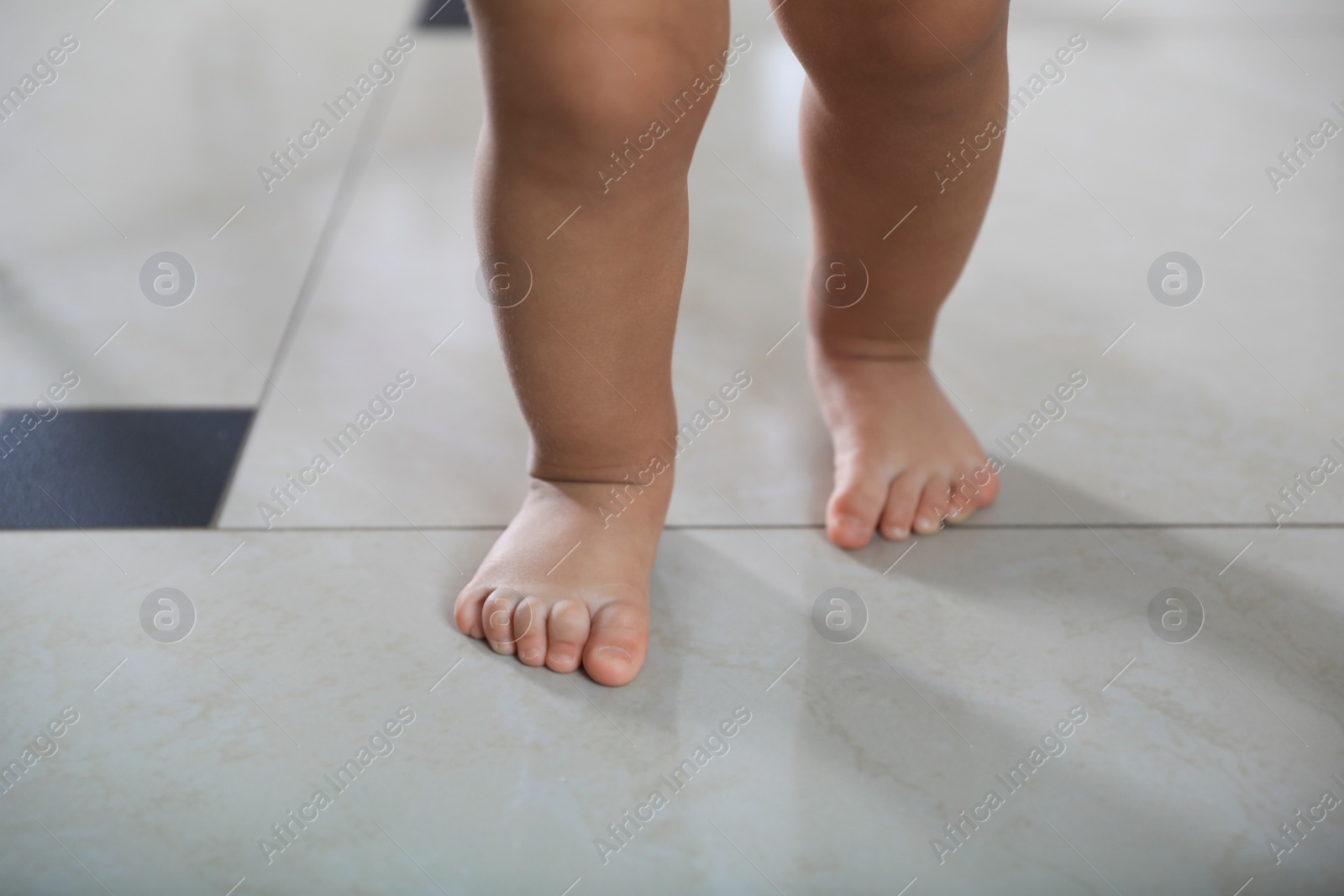 Photo of Cute baby learning to walk indoors, closeup