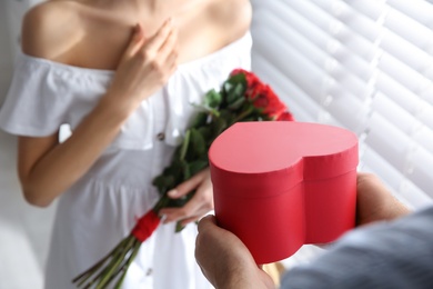 Photo of Man presenting gift to his beloved woman at home, closeup. Valentine's day celebration