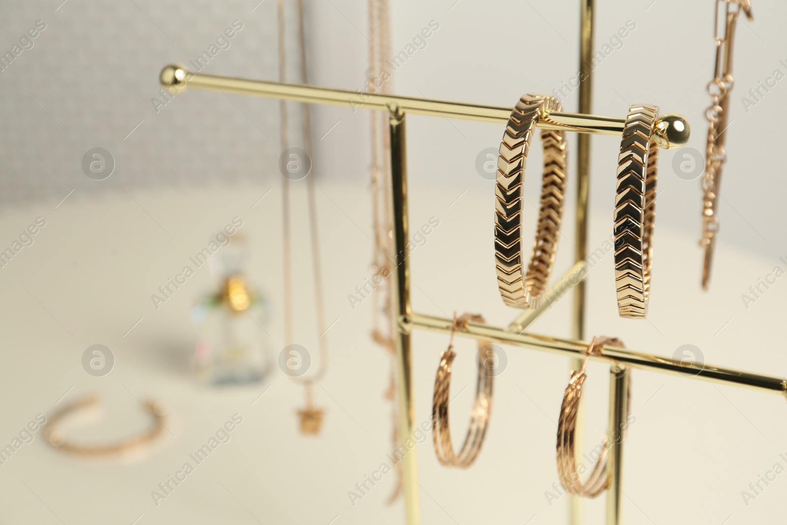 Photo of Holder with set of luxurious jewelry on white table, closeup