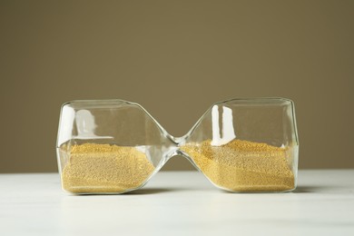 Photo of Hourglass with sand on white table. Menopause concept