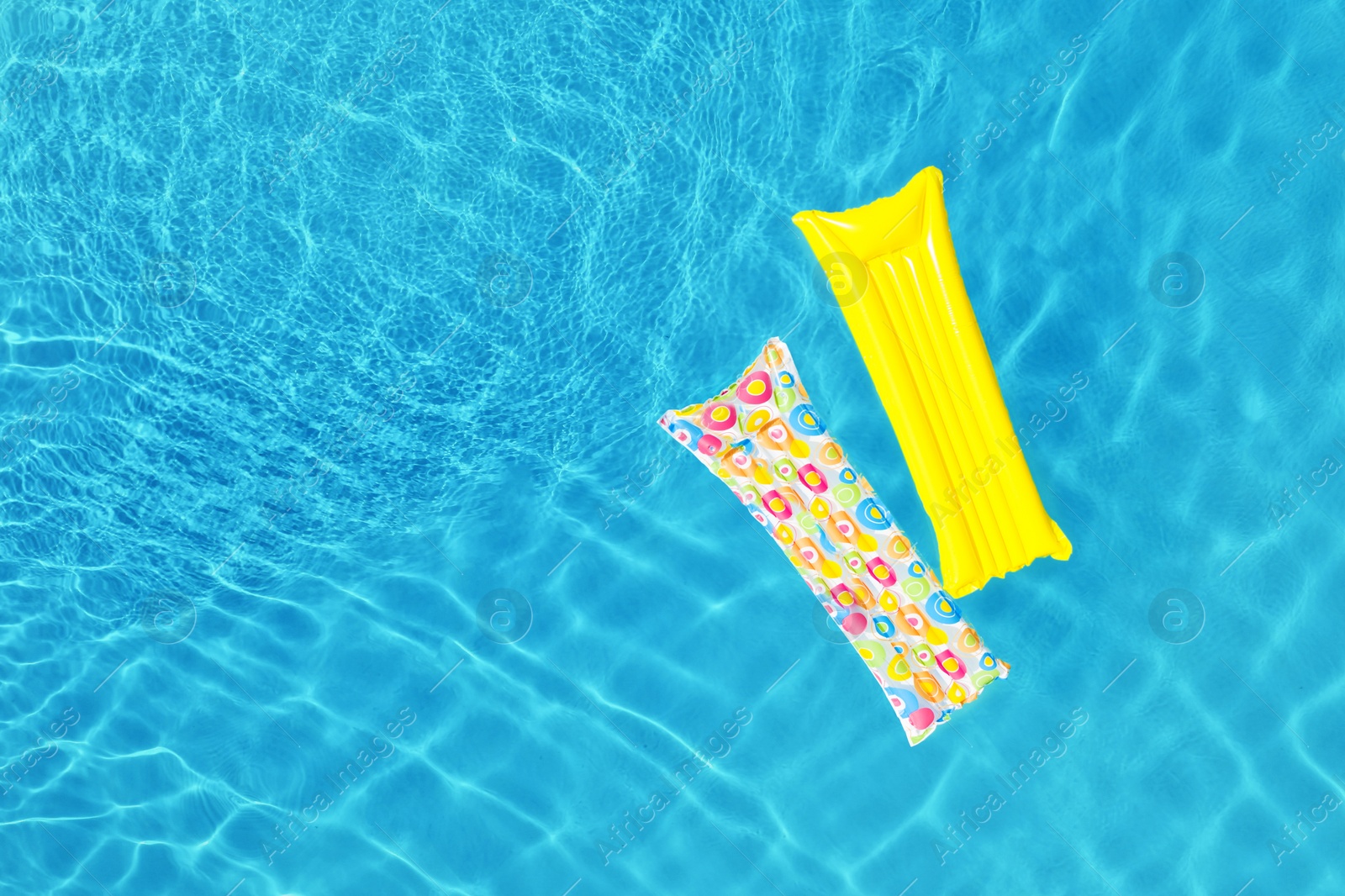 Image of Swimming pool with inflatable mattresses, top view. Space for text