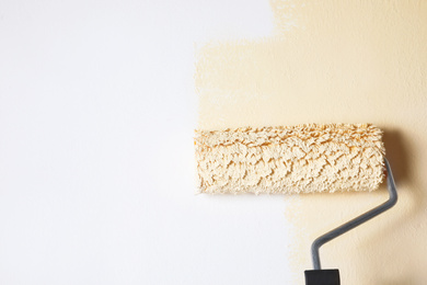 Photo of Painting white wall with beige dye, closeup view. Space for text