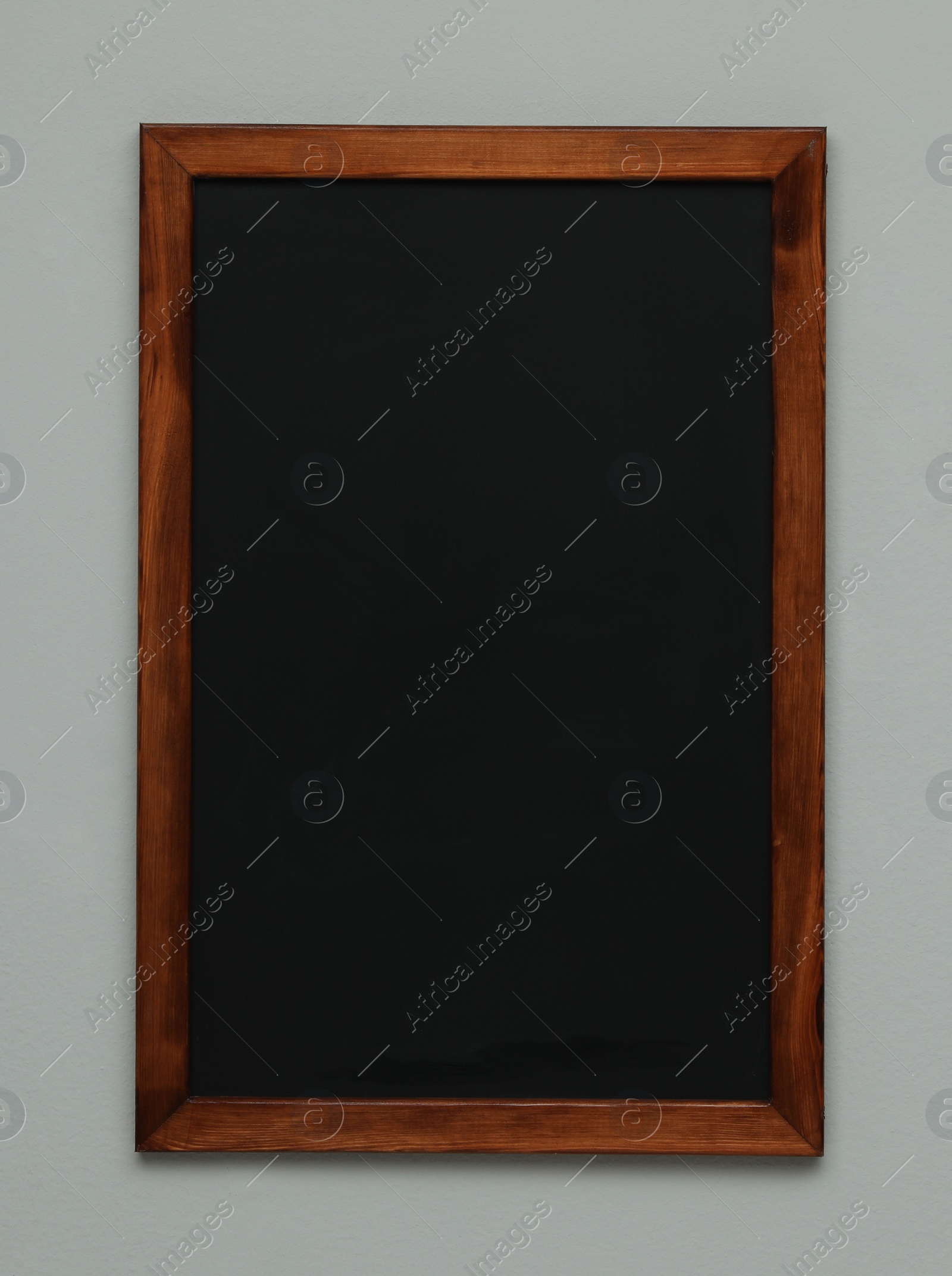 Photo of Clean black chalkboard hanging on grey wall