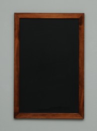 Photo of Clean black chalkboard hanging on grey wall