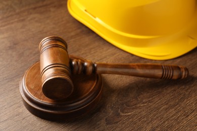 Photo of Law concept. Gavel and yellow hard hat on wooden table