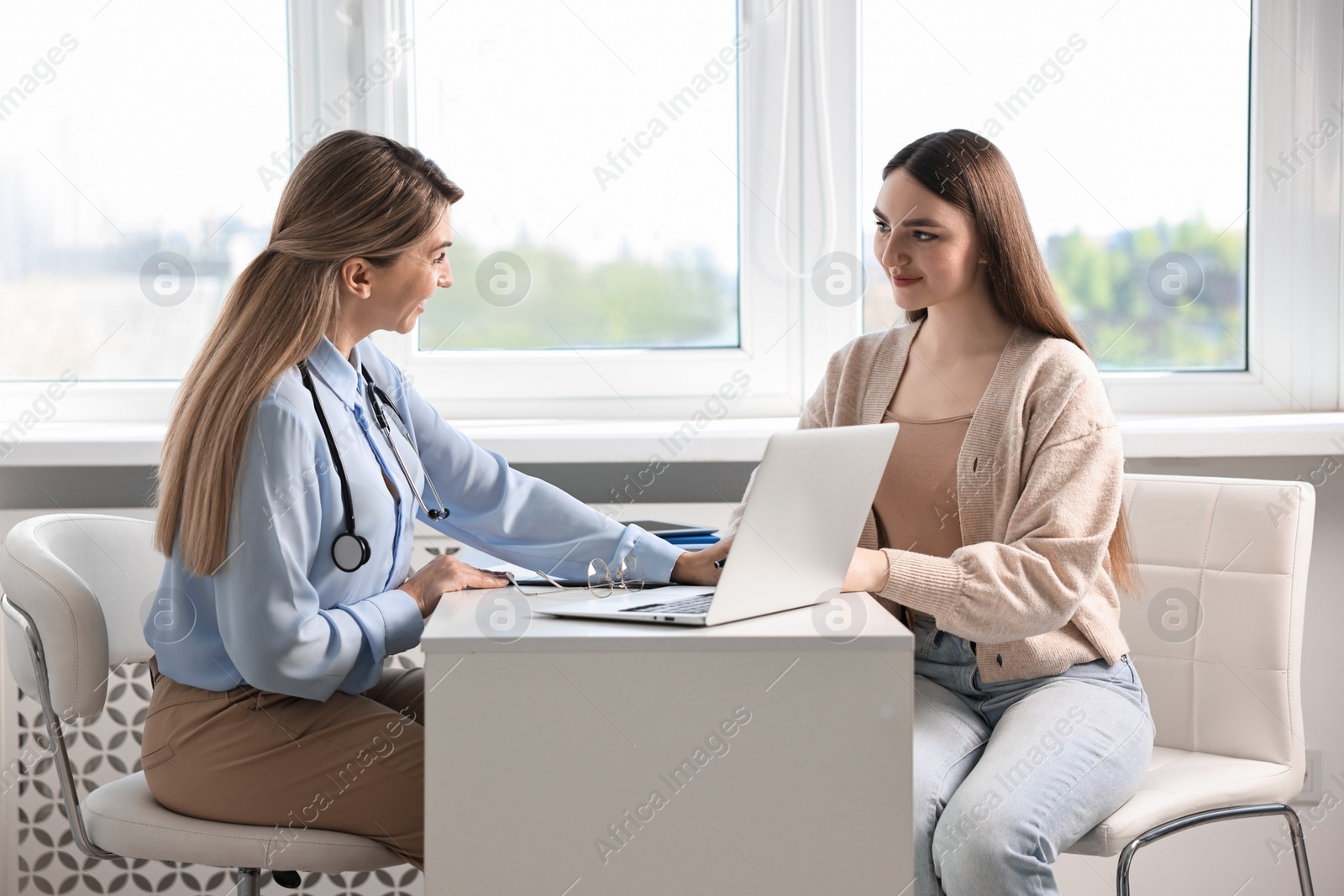 Photo of Professional doctor working with patient at white table in hospital