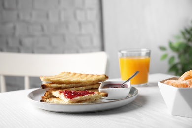 Photo of Tasty toasts with jam served on white wooden table indoors. Space for text