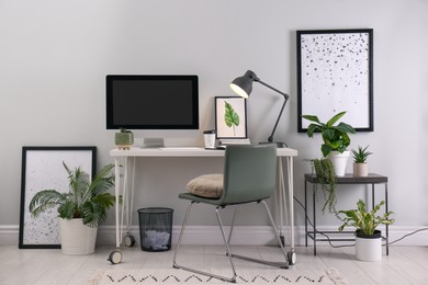Photo of Comfortable workplace with modern computer and houseplants in room. Interior design