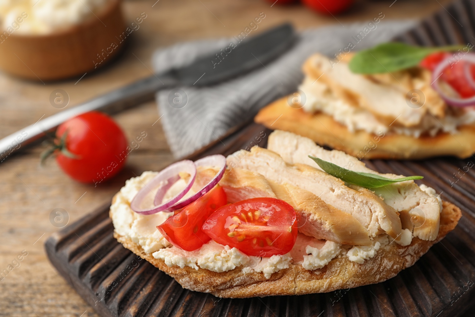 Photo of Board with delicious chicken bruschettas on table, closeup