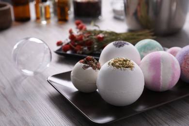 Photo of Plate with different bath bombs on wooden table