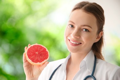 Nutritionist with grapefruit on blurred green background