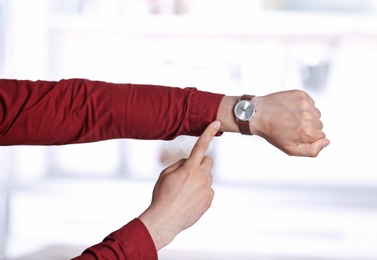 Young man with wristwatch on blurred background, Time concept