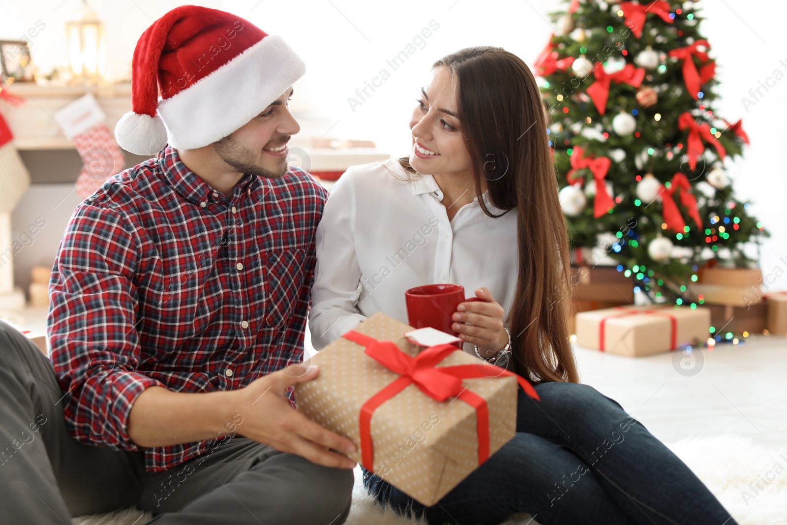 Photo of Young couple with Christmas gift at home