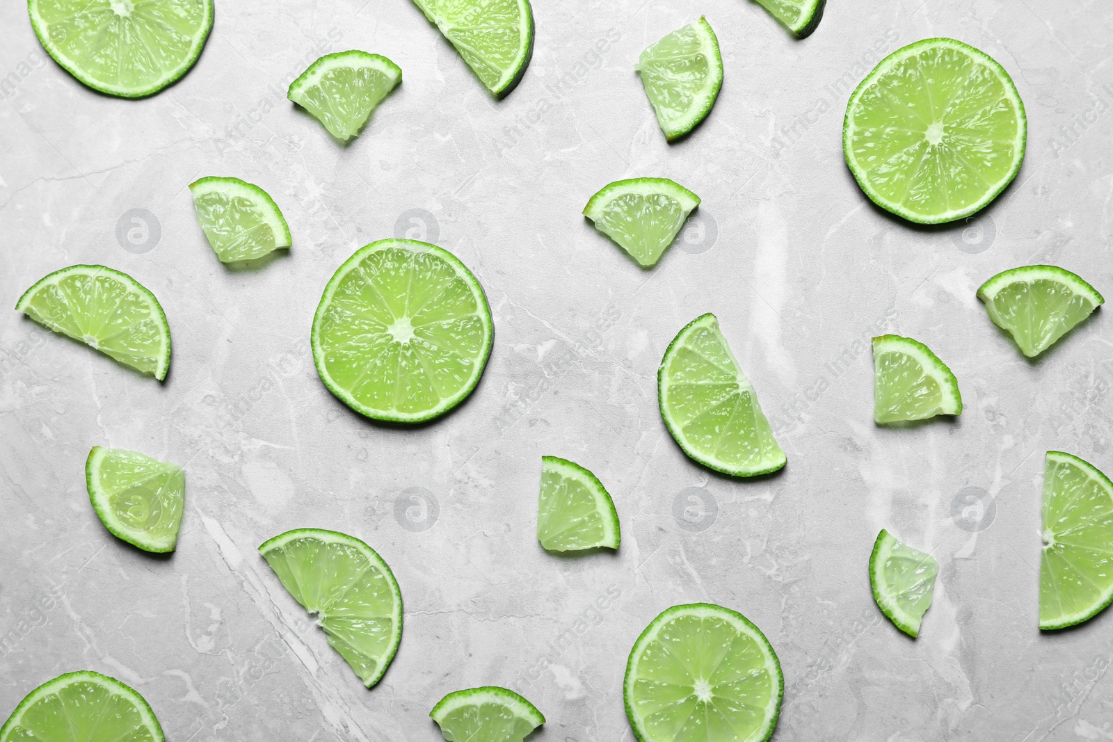 Photo of Slices of fresh juicy lime on marble table, flat lay