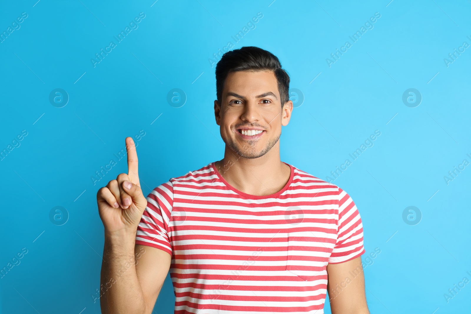 Photo of Man showing number one with his hand on light blue background