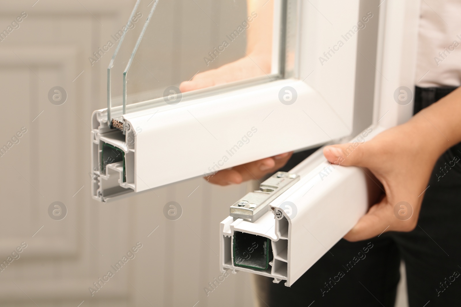 Photo of Woman holding sample of modern window profile on blurred background, closeup