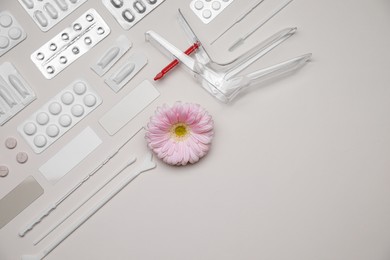 Photo of Sterile gynecological tools, pills and gerbera flower on beige background, flat lay. Space for text