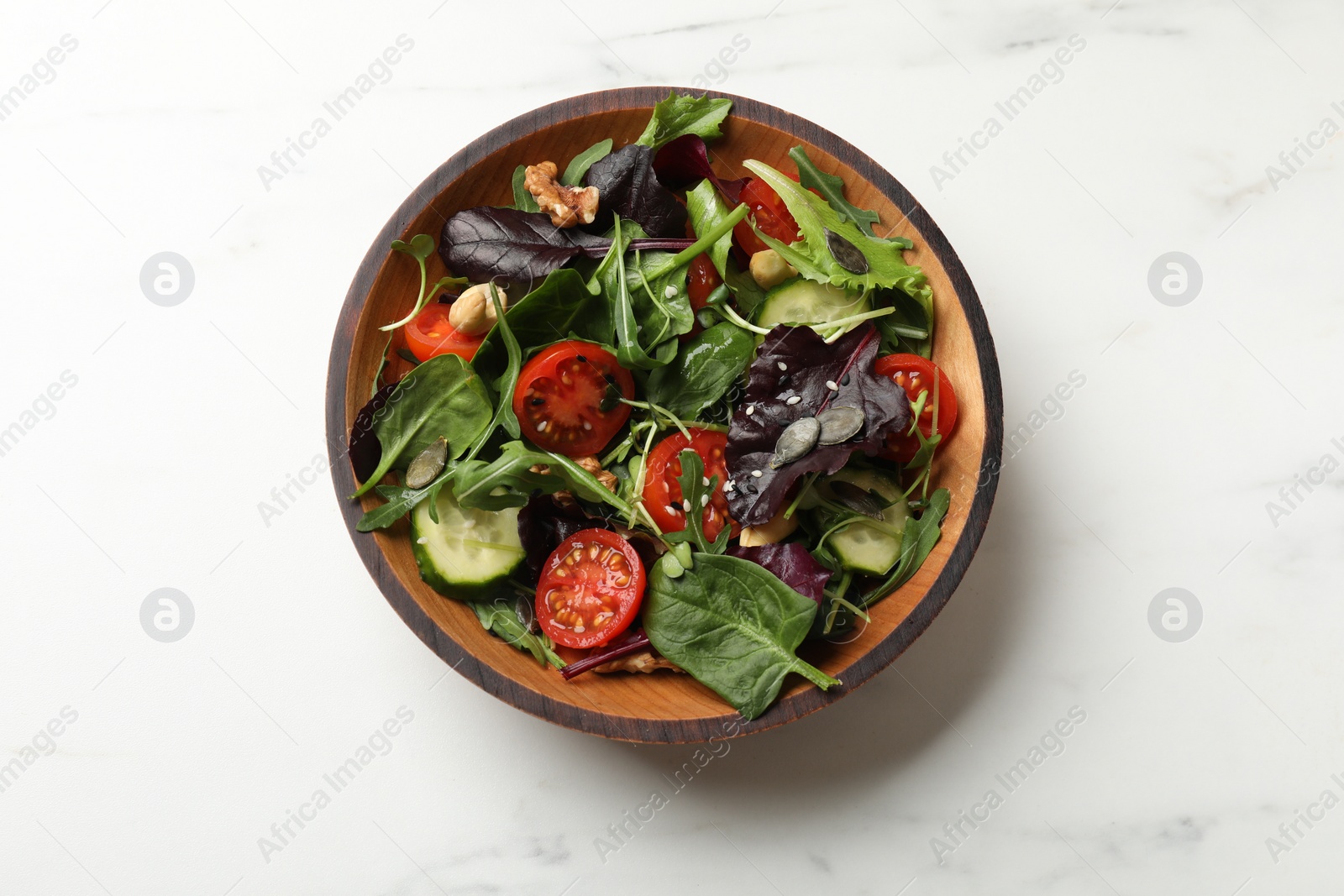 Photo of Tasty fresh vegetarian salad on white marble table, top view