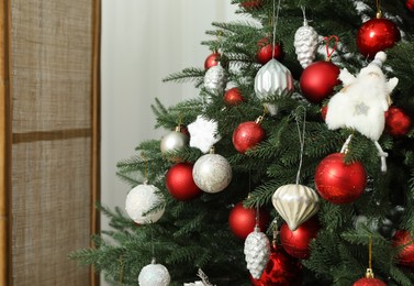 Photo of Christmas tree decorated with beautiful baubles indoors