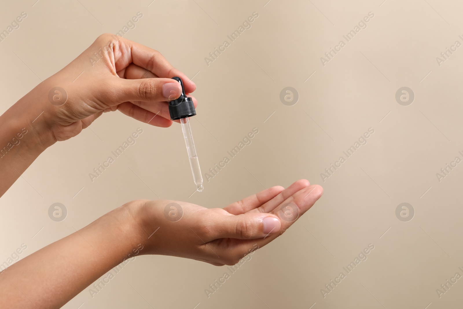 Photo of Woman applying cosmetic serum onto her hand on beige background, closeup. Space for text