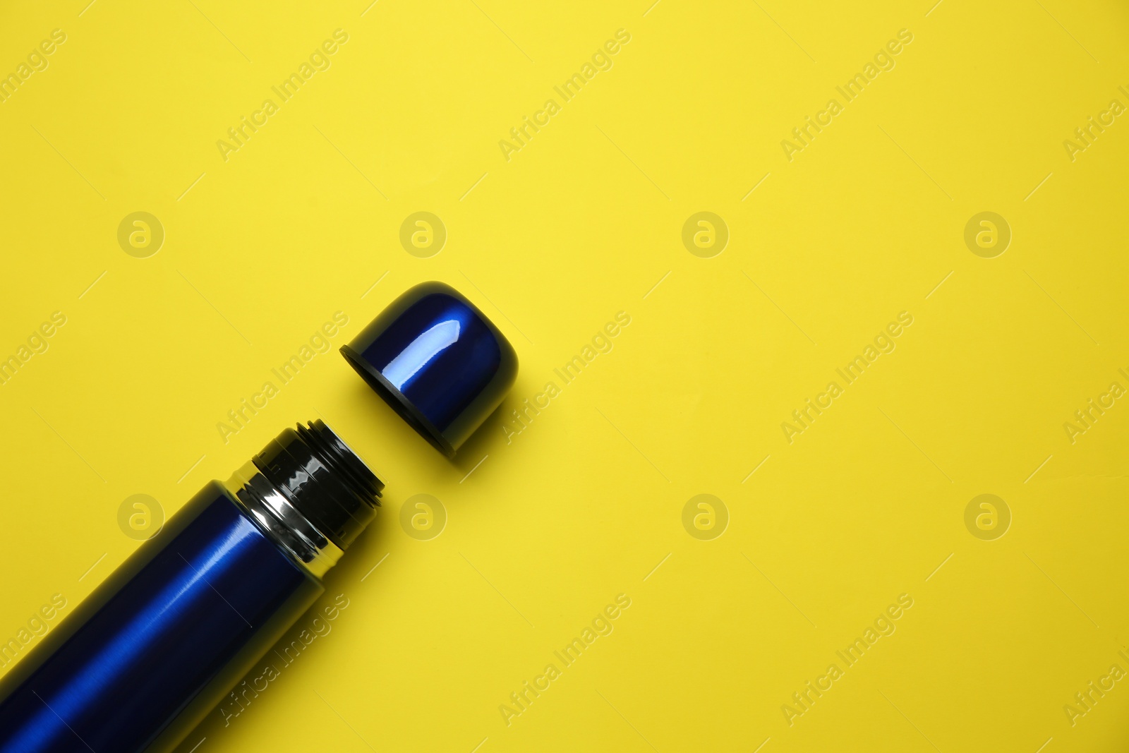 Photo of New modern thermos and cup on yellow background, flat lay. Space for text